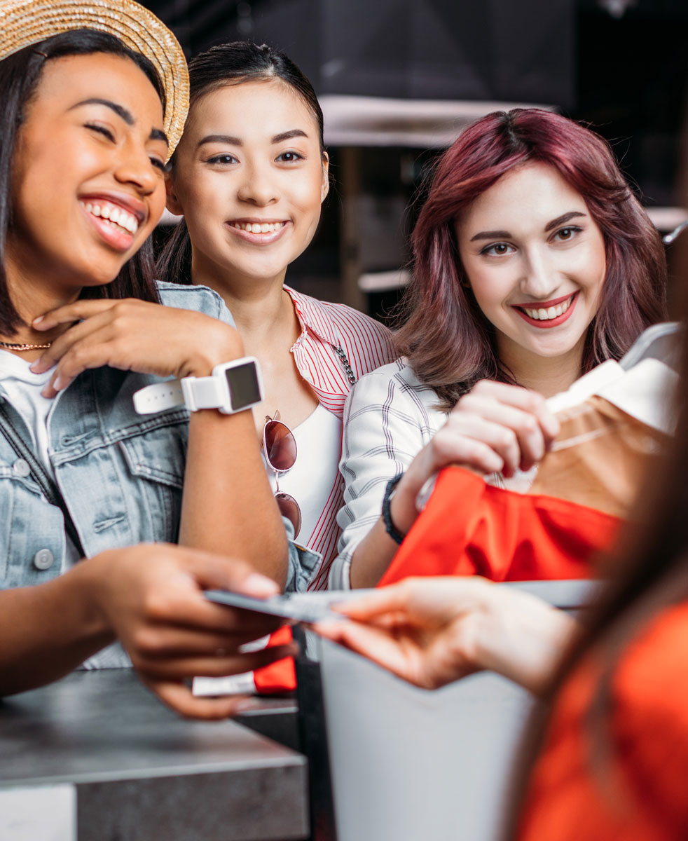 Young women giving a credit card to a cashier using a no fee credit card processing terminal to process a payment